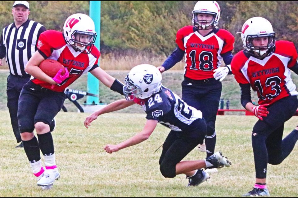 U14 Falcons player Ella Schenher ran with the ball, pushing away a Raiders defender, as QB Cooper Knox (No. 18) watched from behind, in Saturday's game at WMF Field.