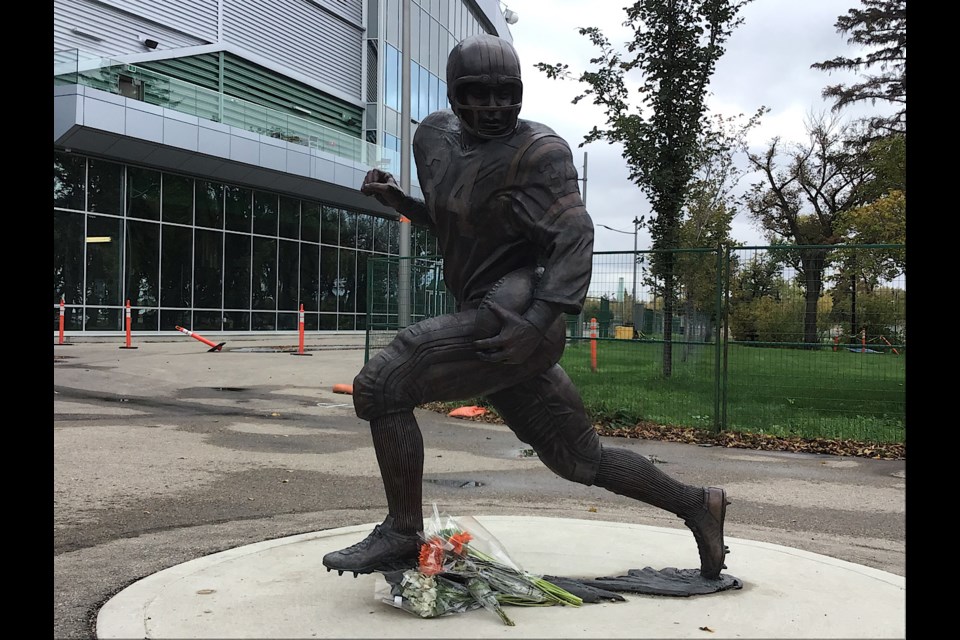 Flowers were left at the statue of George Reed in front of Mosaic Stadium Monday.