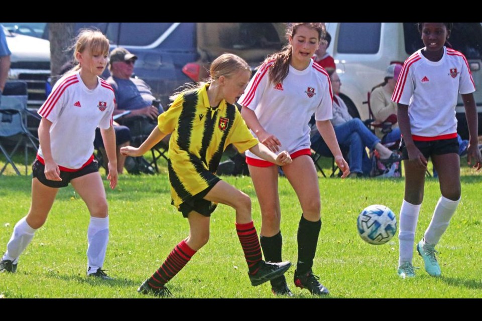 A Weyburn U11 girls player, in yellow, kicked the ball past three defenders from Moose Jaw, during a tournament game on Saturday morning.