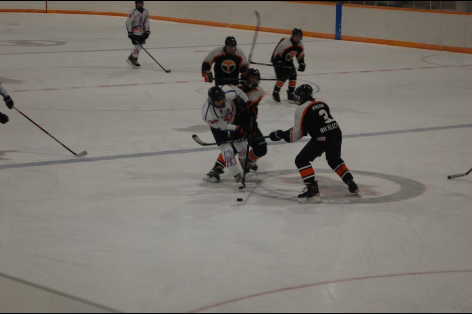 Cole Masley of the Highway 9 Predators U15 hockey team (white jersey) fought for possession of the puck against several opposing players during a home game against Yorkton on January 9. The Predators went on to a 6 to 2 victory. / Liz Jacobsen