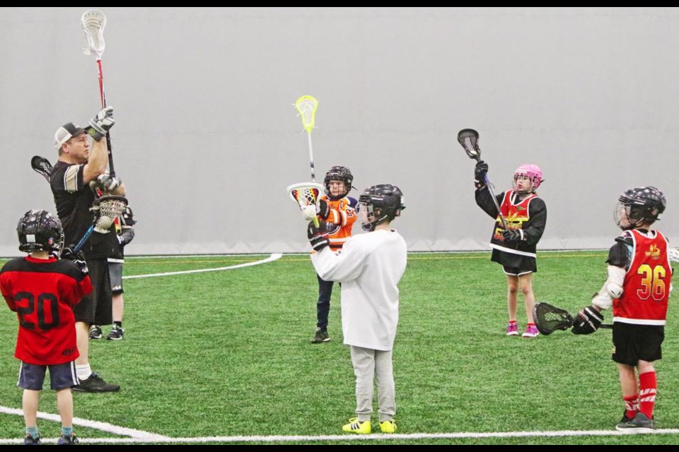 Field lacrosse coach Charles Hignett had all the U10 players raise their sticks, to show the position they should be when passing the ball to a teammate