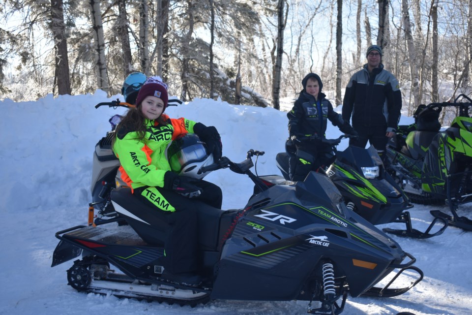 From left, Ivy Andrychuk on her kid-sized snowmobile posed with her buddy Wyatt Gruber for a photo, who is next to his Dad, Travis Gruber