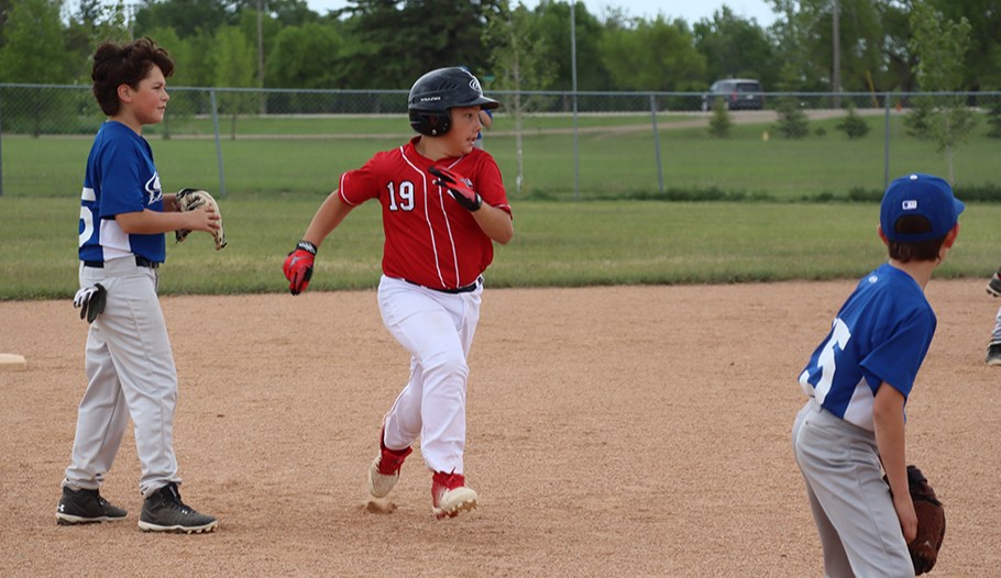 After a wild pitch, Lukas Woicichowski of the 11U Baseball Team 2 kept his eye on the ball as he dashed from second to third during Canora Minor Ball Day on June 14.