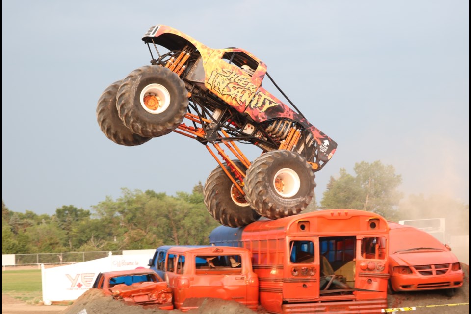 The Sheer Insanity trucks launches over an old bus.