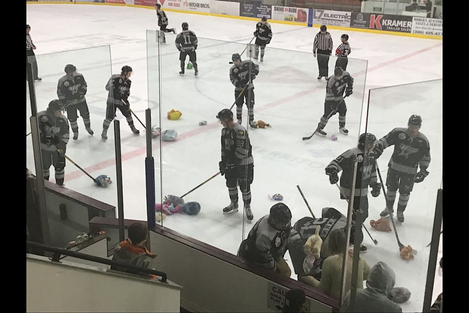The Battlefords North Stars help clean up the teddy bears off the ice following their first goal of the game against Notre Dame Tuesday.