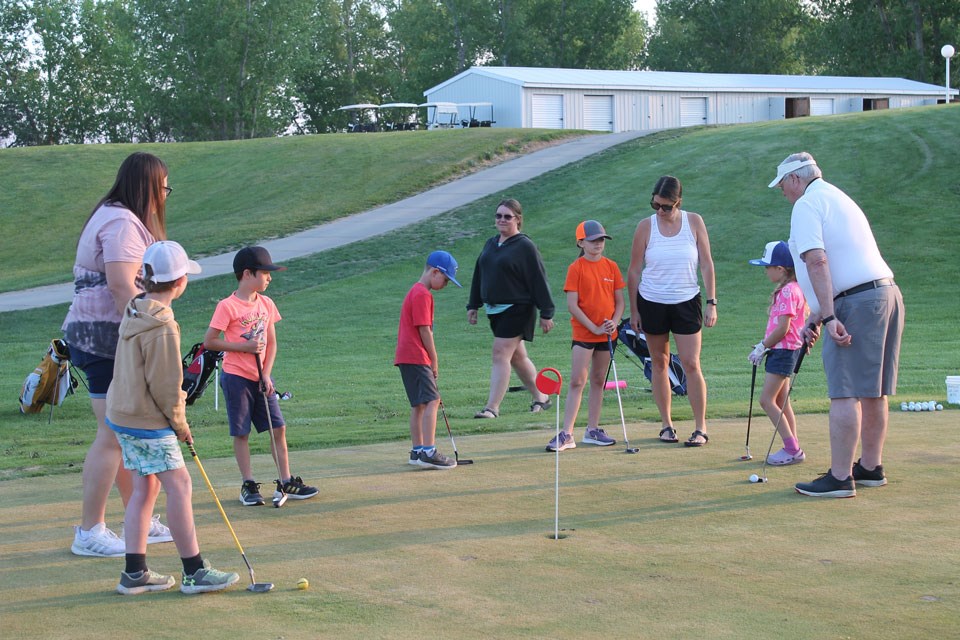 Students and coaches watching as coach Ron Spencer gives some putting advice. 








Cutline #5 – Layden Rusk chips onto the green under the watchful gaze of coaches Ron Spencer and Amanda Purves. Photo submitted by Paul Kimball