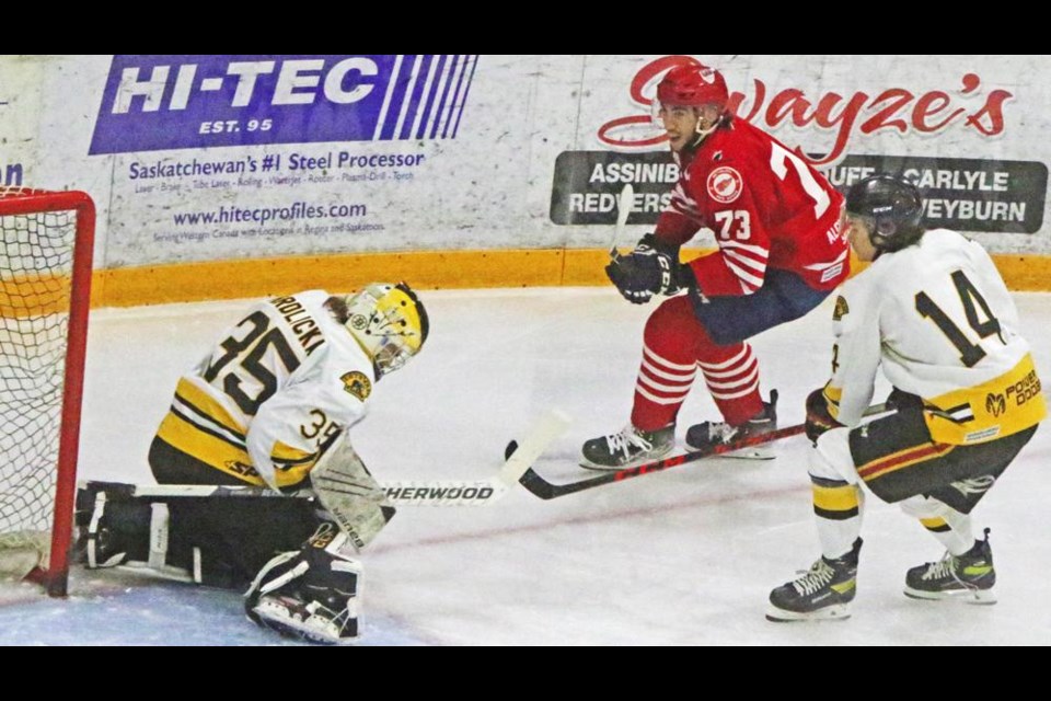 Estevan goalie Cam Hrdlicka covered up after a shot by Red Wings player William Jasmin at right, guarded by Bruins player Linden Perry.