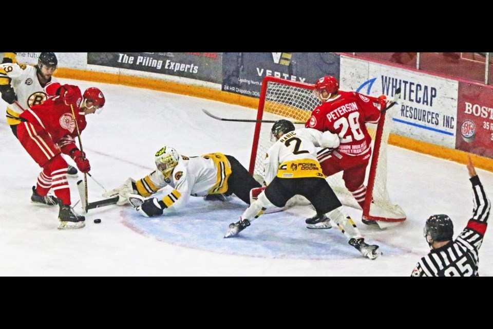 Red Wings centre Drew Kuzma and Estevan Bruins goalie Boston Bilous both go after the loose puck, while Bruins defenceman Aleksa Babic shoves Wings left-winger Shayde Peterson into the net knocking it off the moorings, with the referee set to call him on the penalty.