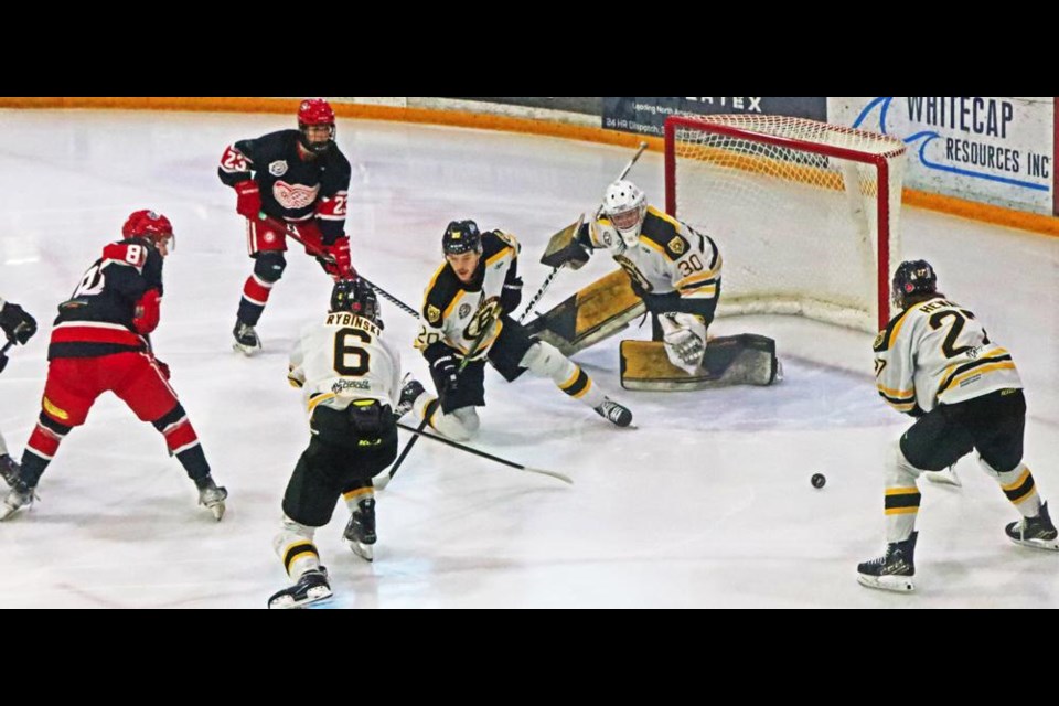 Red Wings players Blake Betson, left, and Connor Bear watch as a Bruin gets ready to fire a loose puck out of the goal crease area on this play.