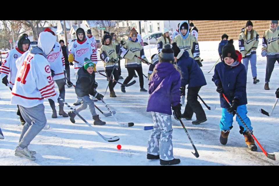 Kids joined in to play the Red Wings and Gold Wings in good old-fashioned road hockey in front of Crescent Point Place on Saturday.