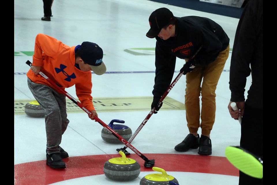 Curling on a team skipped by their grandpa Darcy Zielinski of Canora, Ryley Woicichowski, left, and his big brother Brandyn dragged this rock into the rings at the Canora Town & Country Bonspiel.