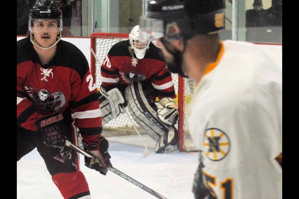 Miners’ Ethan Scherr, backed by goalie Ryan Rewerts, keeps his eye on a Biggar National player early in the first period in a home game Dec 4. 