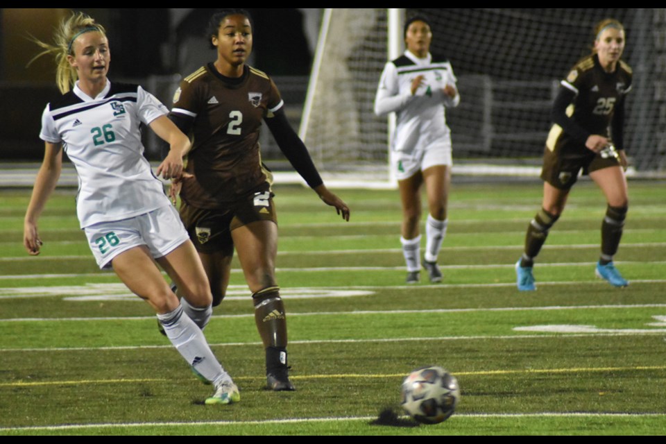 The Huskies' Anna Oliver, left, tries to prevent the Bisons' Janelle Chomini from chasing the ball in their opening match Friday night at Griffiths Stadium.