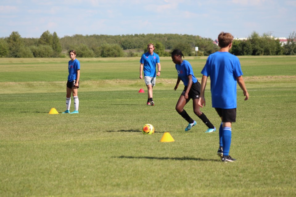 Scott Murchison, pictured here in the center with grey shorts, of the Rangers Football Club directs athletes on the field.