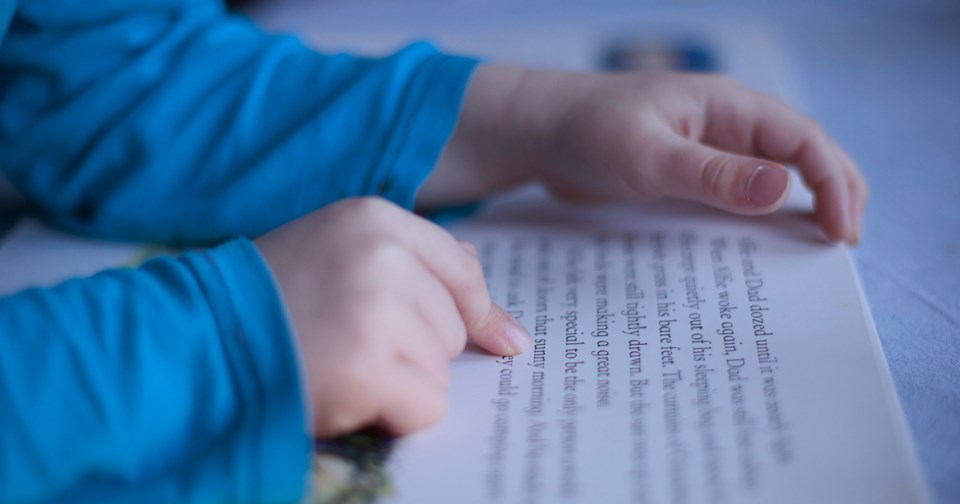 close up boys fingers pointing to words in book