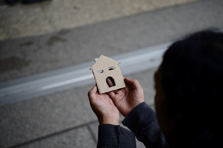 Hands of the man holding the paper house