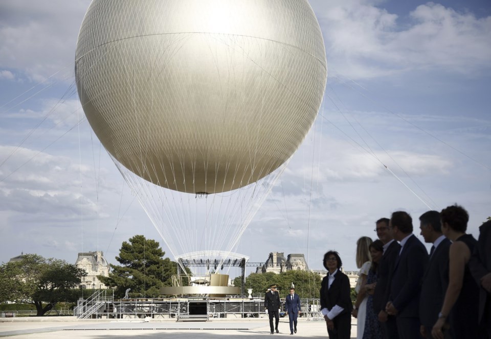 French President Emmanuel Macron, right background, visits the site of the reinstallation of the Olympic cauldron at the Tuileries Garden in Paris, Thursday, June 12, 2025. (Yoan Valat/Pool Photo via AP)