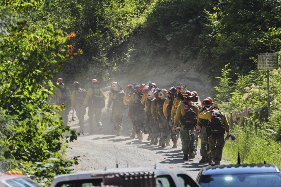 A line of wildland firefighters arrive at the scene the day after a shooter ambushed and killed multiple firefighters responding to a wildfire at Canfield Mountain Monday, June 30, 2025, in Coeur D'Alene, Idaho. (AP Photo/Lindsey Wasson)