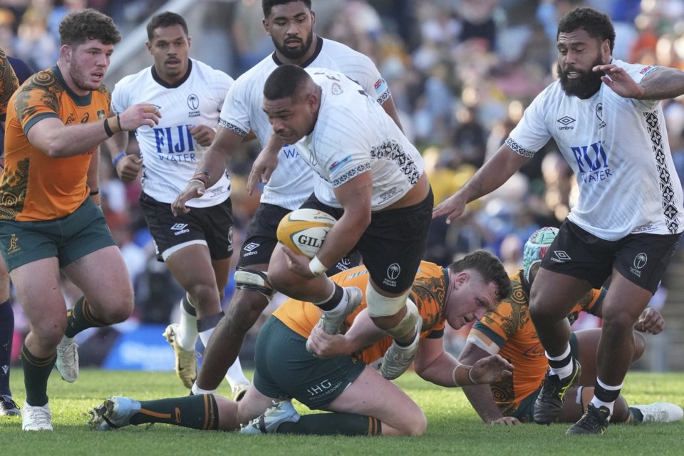 Fiji's Sam Matavesi, center, is tripped up by Australia's Angus Bell during their rugby union international match in Newcastle, Australia, Sunday, July 6, 2025. (AP Photo/Mark Baker)