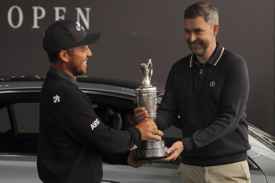 Xander Schauffele of the United States, left, winner of the 2024 British Open, hands back the Claret Jug trophy to the R&A CEO Mark Darbon ahead of the 2025 British Open golf championship at the Royal Portrush Golf Club, Northern Ireland, Monday, July 14, 2025. (AP Photo/Fransisco Seco)