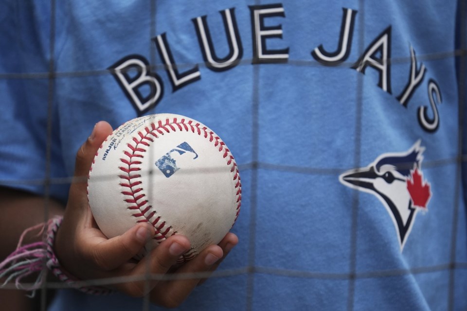 A Toronto Blue Jays fan holds a ball as he waits to get an autograph from players before the start of a baseball game between the Blue Jays and the White Sox in Chicago on Wednesday, July 9, 2025. (AP Photo/Nam Y. Huh)