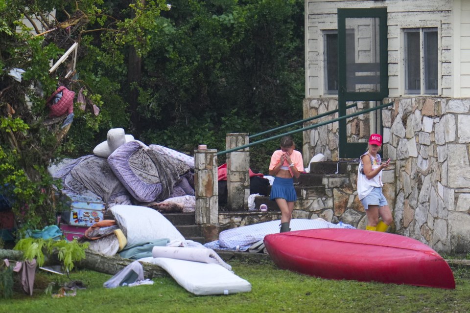 A person reacts while looking at the belongings outside sleeping quarters at Camp Mystic along the banks of the Guadalupe River after a flash flood swept through the area Sunday, July 6, 2025, in Hunt, Texas. (AP Photo/Julio Cortez)