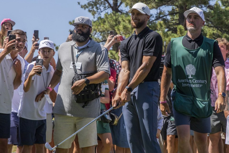 Stephen Curry hits from the spectator area on the 18th hole during the first round of the American Century celebrity golf tournament at Edgewood Tahoe Golf Course in Stateline, Nevada, on Friday, July 11, 2025. His caddie Jason Richards, right, is seen next to him. (Santiago Mejia/San Francisco Chronicle via AP)