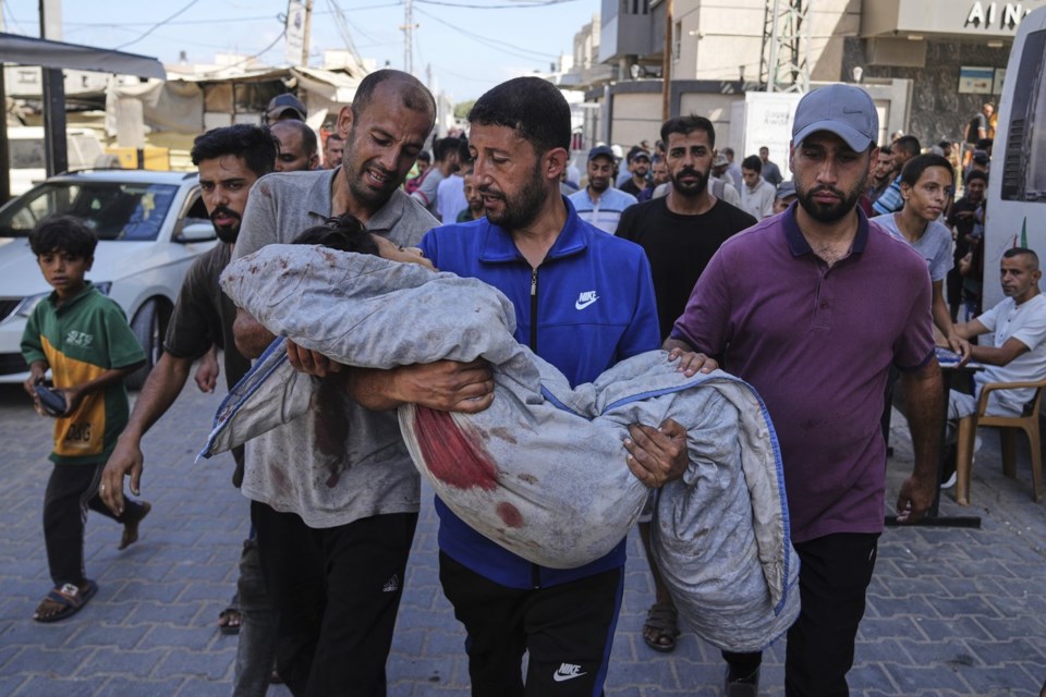 Relatives carry the body of 13-year-old Seraje Ebrahim, killed in an Israeli strike on a drinking water distribution point, for burial outside Al-Awda Hospital in Nuseirat, central Gaza Strip, Sunday, July 13, 2025. (AP Photo/Abdel Kareem Hana)