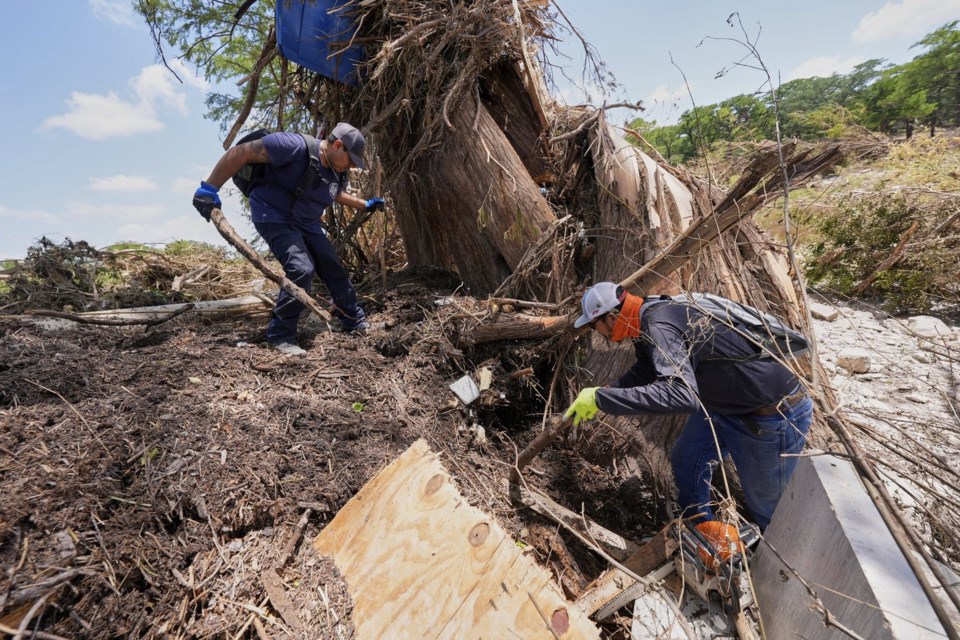 Volunteer Mario Rios, right, and a fellow volunteer, search along the bank of the river after flash floods along the Guadalupe River in Kerrville, Texas, Thursday, July 10, 2025. (AP Photo/Gerald Herbert)