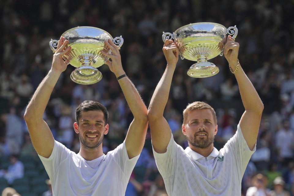 Julian Cash of Britain, left, and Lloyd Glasspool of Britain celebrate with the trophy after winning the men's doubles final match against Rinky Hijikata of Australia and David Pel of the Netherlands at the Wimbledon Tennis Championships in London, Saturday, July 12, 2025. (AP Photo/Kin Cheung)