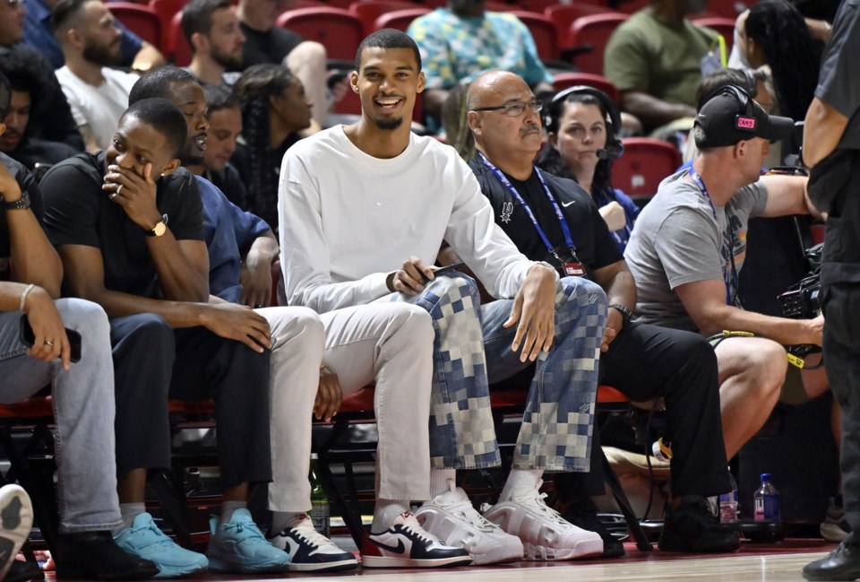 San Antonio Spurs' Victor Wembanyama, center, sits court side during the first half of an NBA summer league basketball game between the Spurs and Philadelphia 76ers, Thursday, July 10, 2025, in Las Vegas. (AP Photo/David Becker)