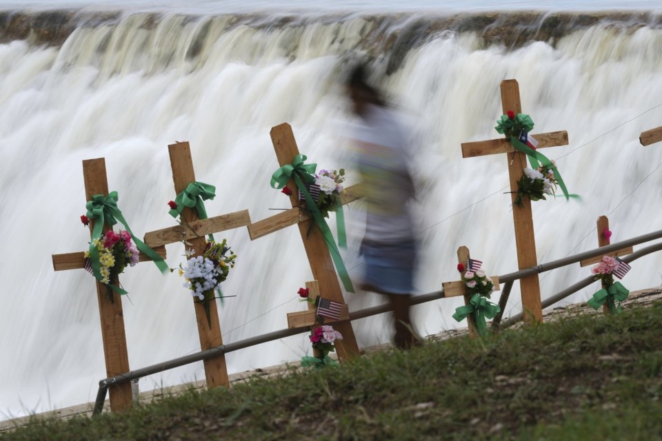 A young girl runs past crosses at a make-shift memorial honoring flood victims, Sunday, July 13, 2025, in Kerrville, Texas. (AP Photo/Eric Gay)