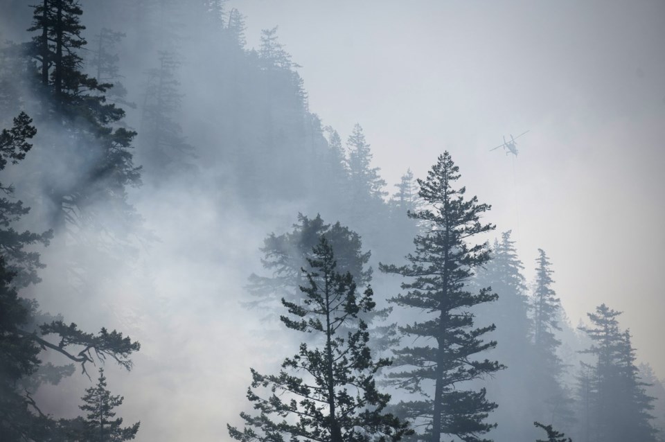 A helicopter prepares to drop water on the Dryden Creek Wildfire, just north of Squamish, B.C., on Wednesday, June 11, 2025. THE CANADIAN PRESS/ Tijana Martin