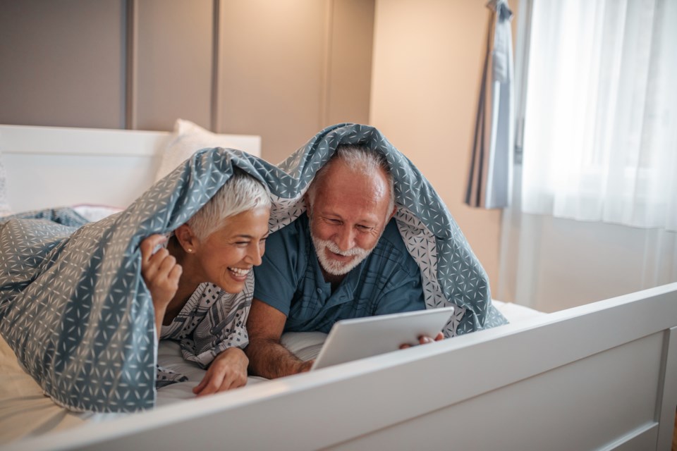 seniors snuggling with tablet stock