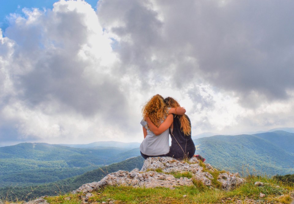 women hugging on a mountain stock