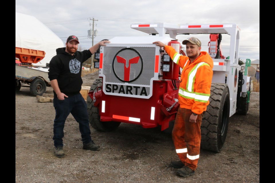 TES Inc. employees at left Clayton Lewis, manufacturing production supervisor, and Riley Easveld, industrial electrician, posed with one of the company’s well-known SPARTA boom trucks that will be tested underground using dynaCERT’s HydraGEN™ fuel economy unit. 