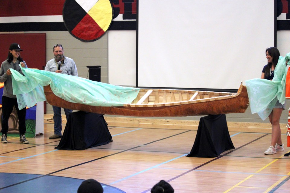 Algonquin Avenue Public School Grade 8 student Roman Nodin, left, principal Darren Lentz and FNMI student support worker Miss Jess unveil a birch bark canoe that the Grade 8 class have been building for the last year. 