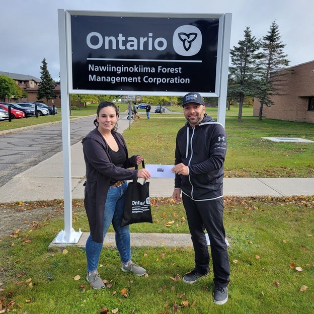 Cassandra Cress, Biigtigong Nishnaabeg Consultation and Governance Officer, accepts a donation from Carmelo Notarbartolo, NFMC general manager. (Facebook)