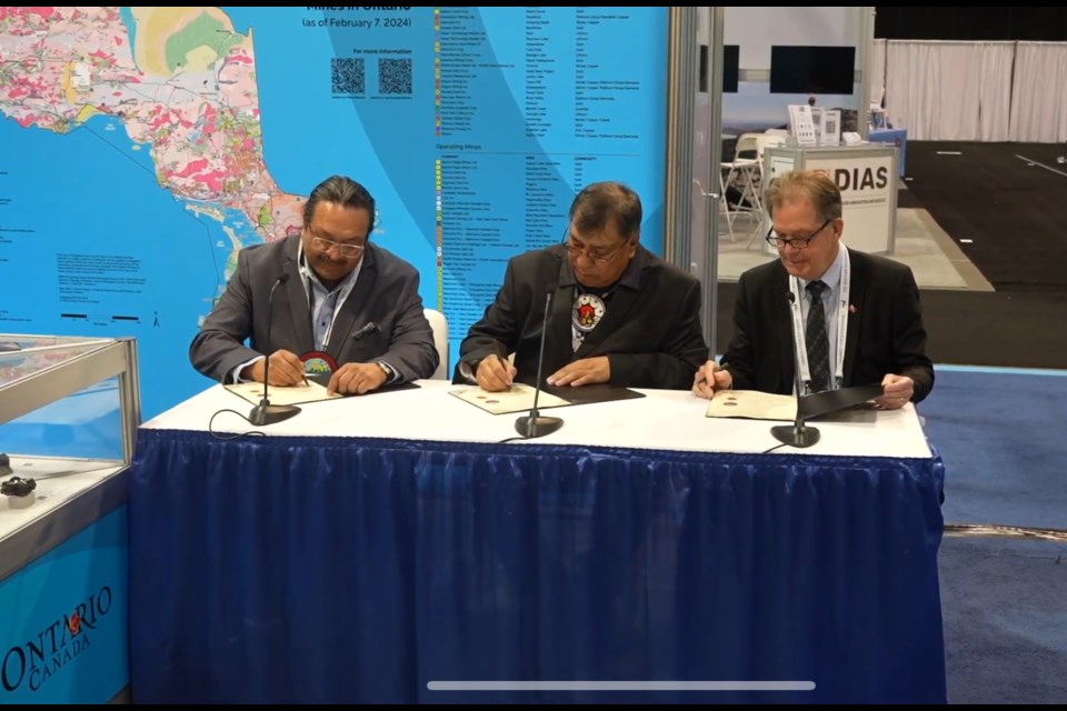 Chief Achneepineskum, Chief Wabasse, and Minister George Pirie sign the Community Development Aid Agreement in front of onlookers on March 5, 2024.