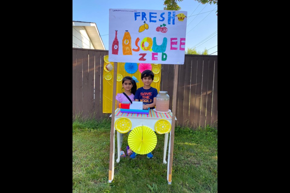 Abrish Eman and Hanzalah Jadoon at their lemonade stand with a homemade sign reading "Fresh Squeezed". Photo supplied