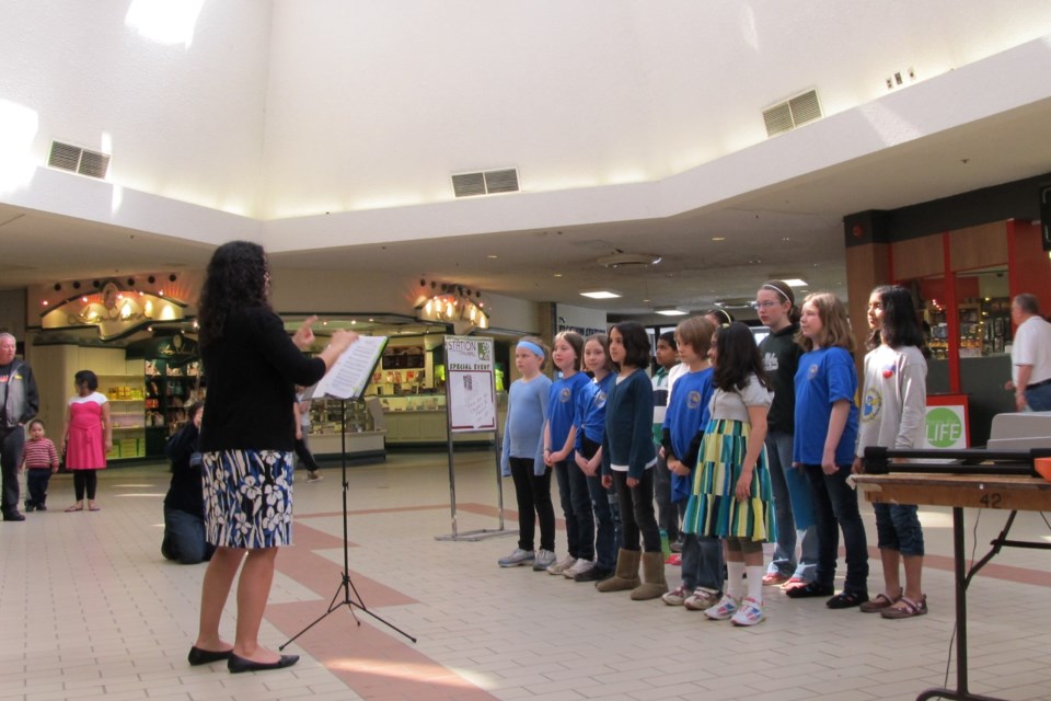 Music teacher Christine Horst is seen directing her students during a live choir performance at the Station Mall.