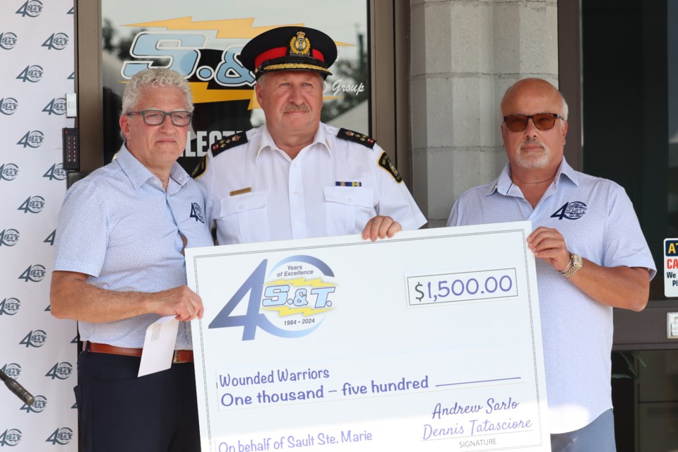 Sault Ste. Marie Police Chief Hugh Stevenson is presented with a cheque for Wounded Warriors Canada from S.&T. co-founders Andrew Sarlo and Dennis Tatasciore.