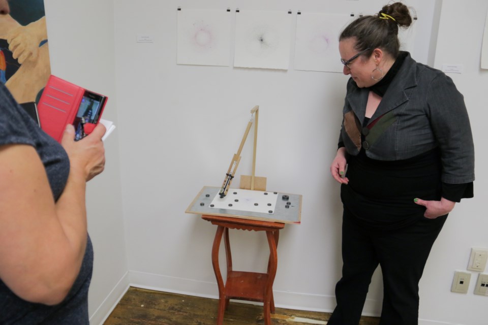 Miinikaan Project project liaison Isabelle Michaud uses exhibiting artist Kyrstiana Bourdage's 'Pulse' prototype drawing device at the Dawaa Dazhi Gallery opening on Saturday. Jeff Klassen/SooToday