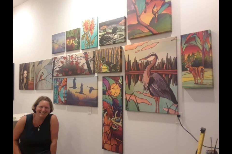 Sherie Gladu with wall of her art in studio. Photo provided by Sherie Gladu.