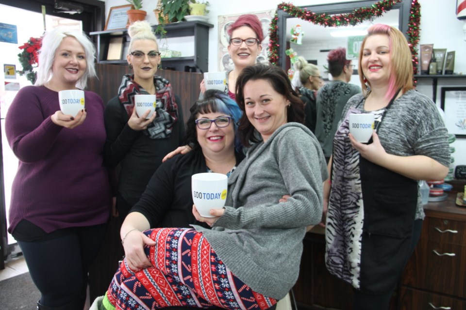 Hairstylists Kristyn Rathbone, Leah Currie, Catherine Moore, Catherine O’Donnell (owner/operator of Catherine’s Hairstyling and Barbershop, seated), Tanya Vezina (on Catherine’s knee) and Jennifer Green with their complimentary SooToday coffee mugs, Dec. 20, 2017. Darren Taylor/SooToday
