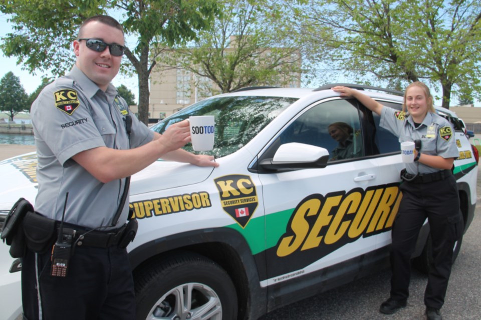 Daniel Laprade, KC Security Services president, and Kaija Kokkinen, security guard, with the company vehicle and two complimentary SooToday coffee mugs, June 20, 2018. Darren Taylor/SooToday