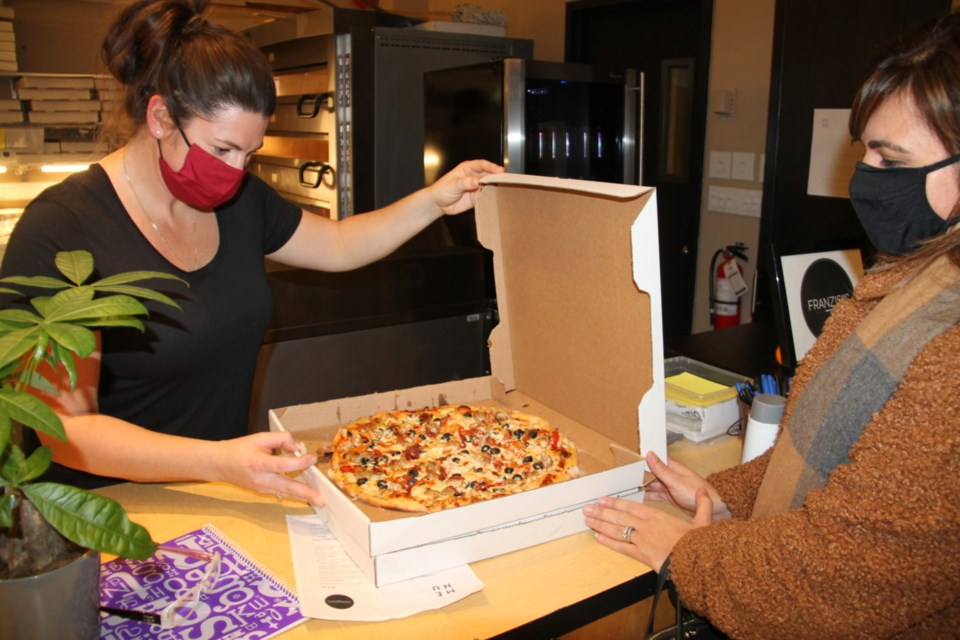 Heather Pusch of Franzisi’s Restaurant serves pizza to a customer at the recently opened Sault Activities Centre, Dec. 4, 2020. Darren Taylor/SooToday