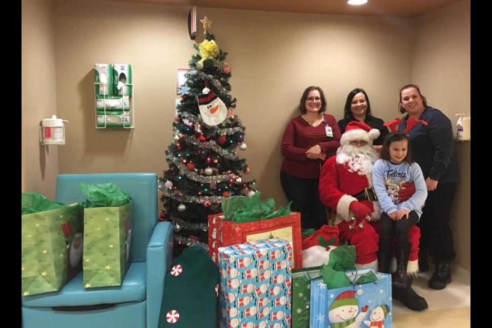 Amanda Johnston and Heather Hilderley-Phillips, with Kierston Miron, Sault Area Hospital’s women and children’s health program manager (at left), with Santa Claus and a young friend as Amanda and Heather delivered Christmas gifts to sick children and their parents at SAH’s Neonatal Intensive Care Unit, Dec. 23, 2017. Photo supplied by Amanda Johnston.