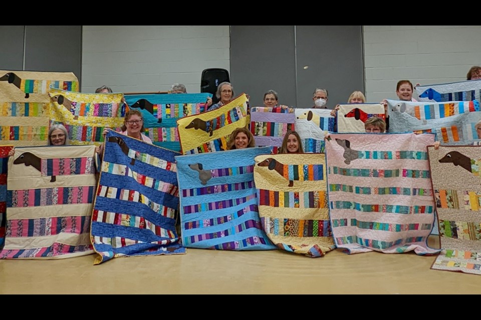 Members holding their quilts with Karen Lefave, director of the Twinkie Foundation, at centre.