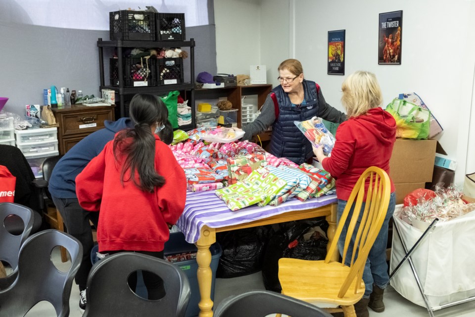 SOYA founder Connie Raynor-Elliott (centre) and volunteers prepare dozens of free gifts prior to a gift-giving event on Tuesday at its Gore Street depot.